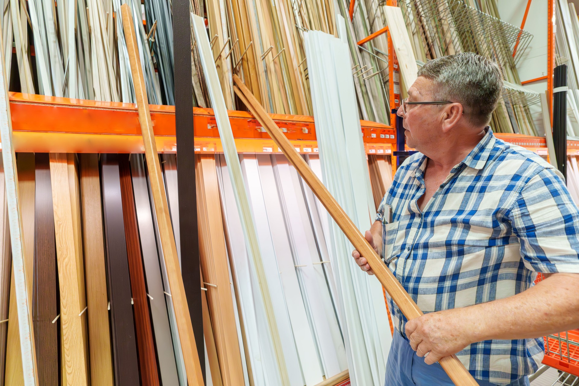 Man Selecting Wooden Molding from Store Display in Hardware Store