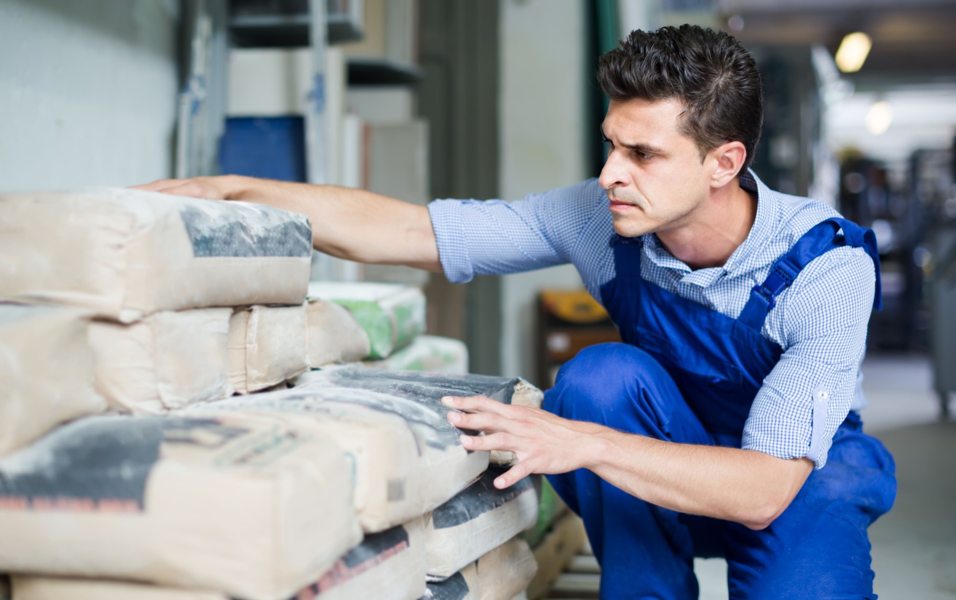 interested male in uniform is choosing cement in the building store